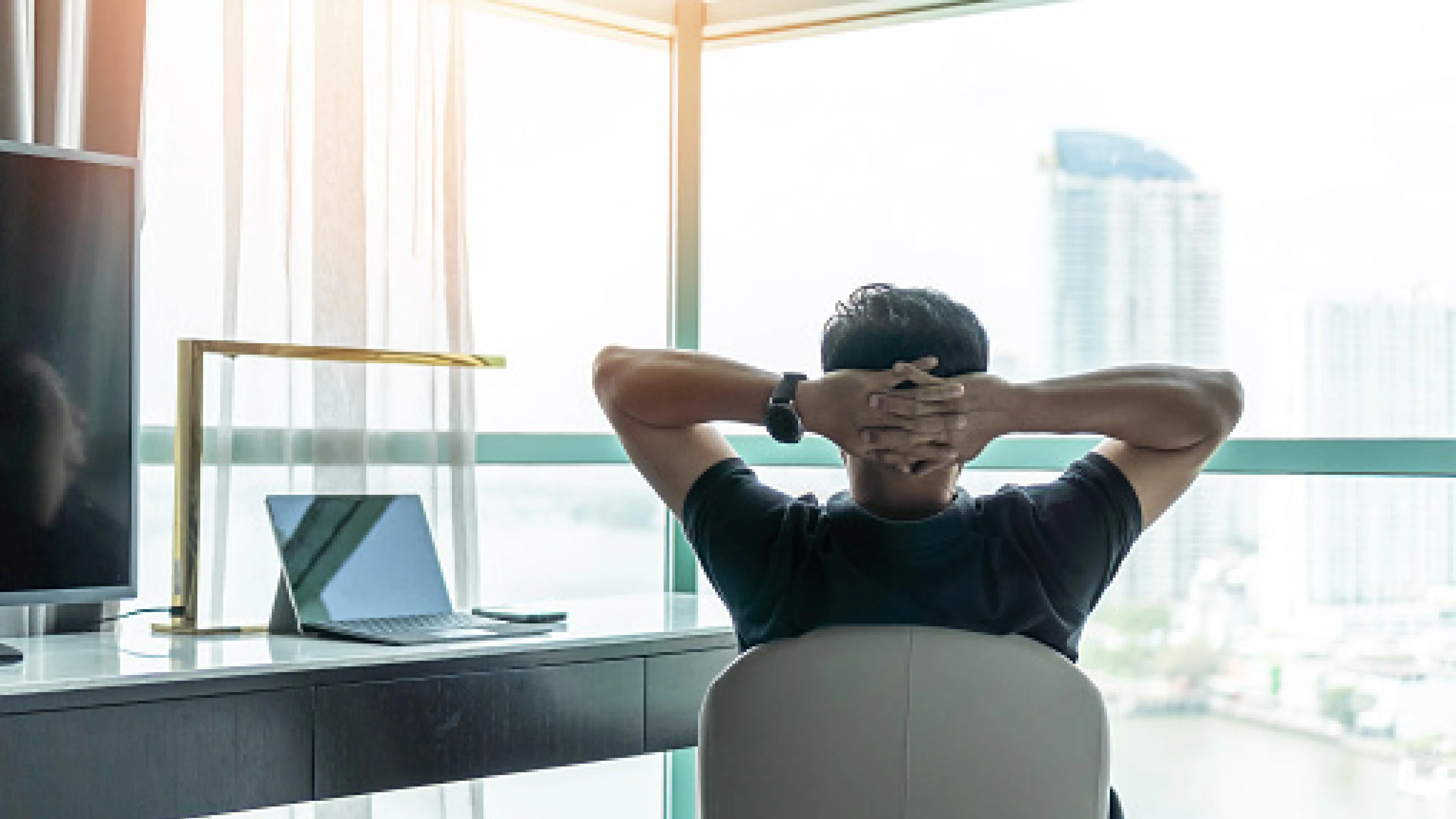 Man sitting in chair with hands relaxing behind head