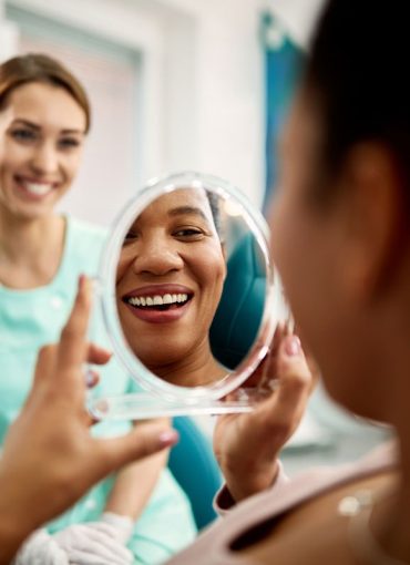 Dental patient looking at mirror with big smile